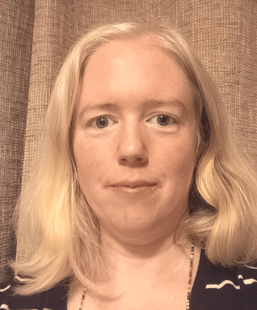 Photo of Lorna. She has blonde/gray hair and wears a black and white striped top.